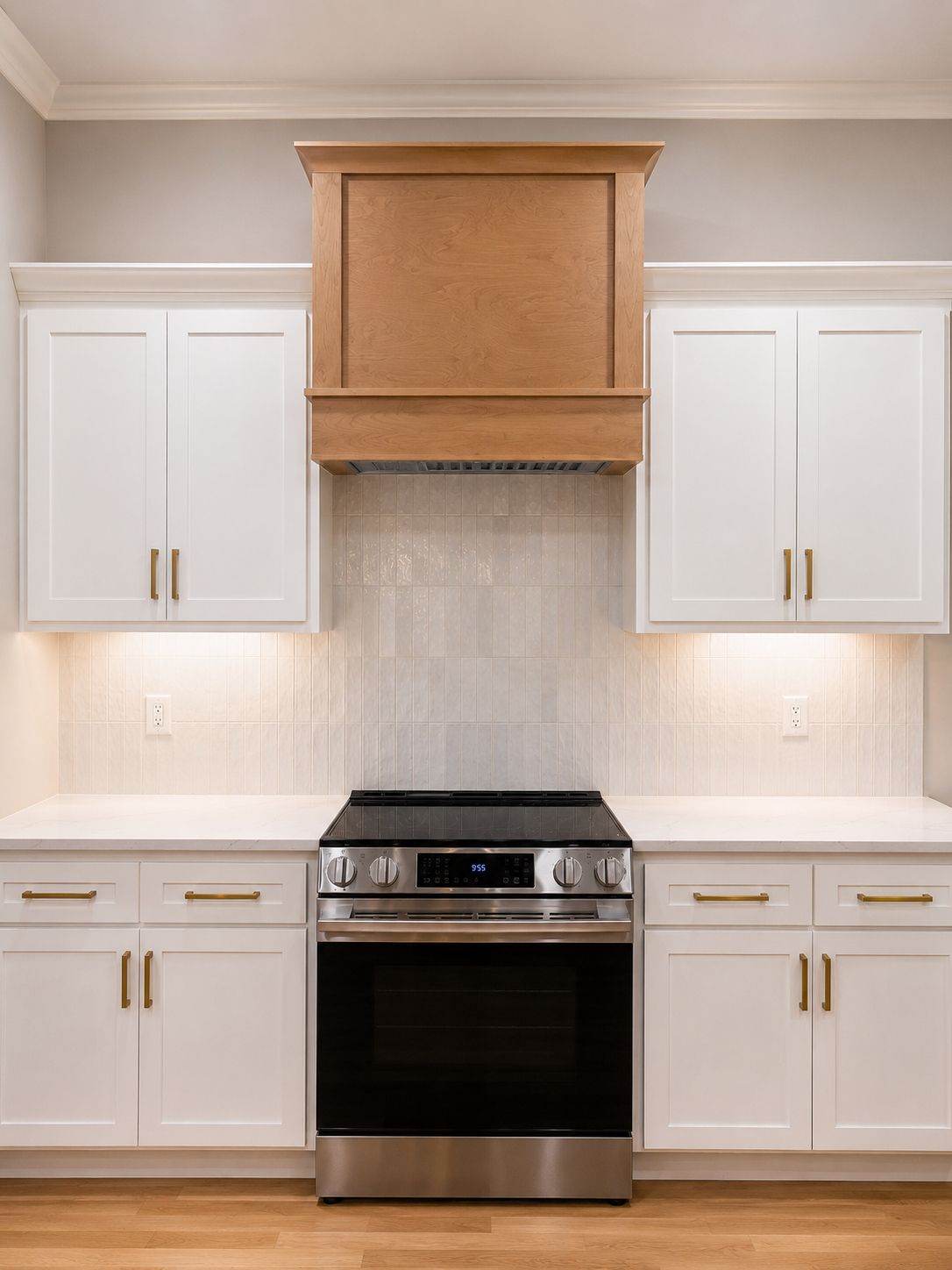 Custom kitchen cabinetry detail from a Raymore kitchen remodel by Resurrection Homes with a wood vent hood, white shaker cabinets, and brass hardware