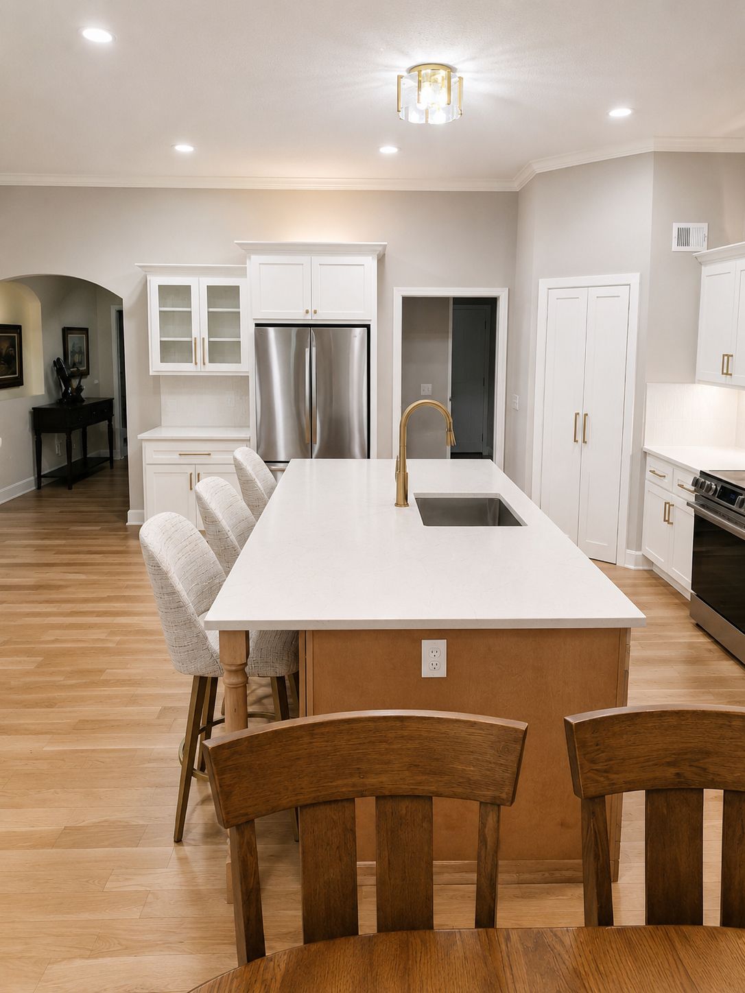 Finished kitchen remodel in Raymore by Resurrection Homes with white shaker cabinetry, a quartz island with seating, and a stainless refrigerator