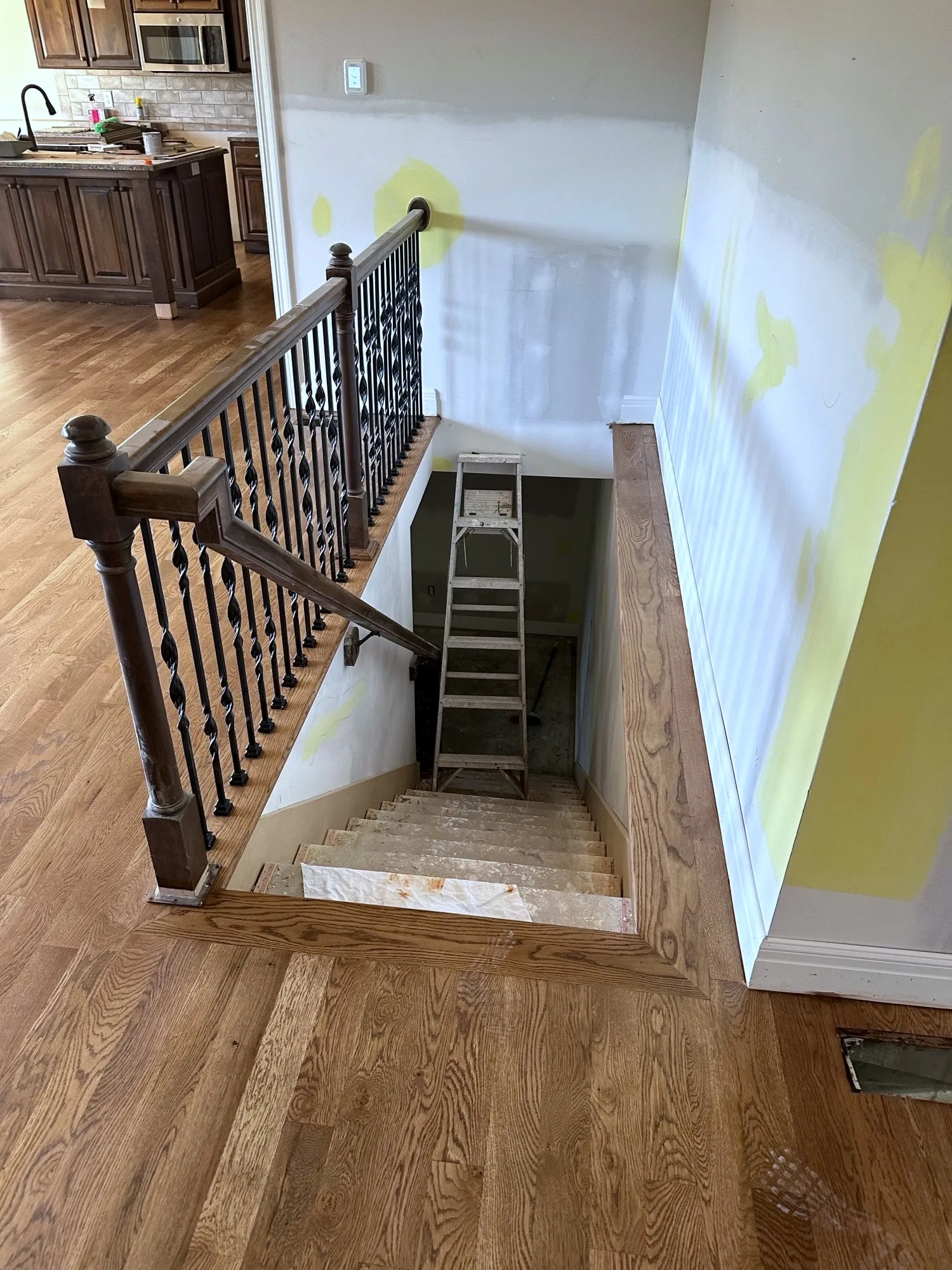 Stair opening with walls patched for paint and new oak flooring at the landing in a Holden, Missouri whole home remodel