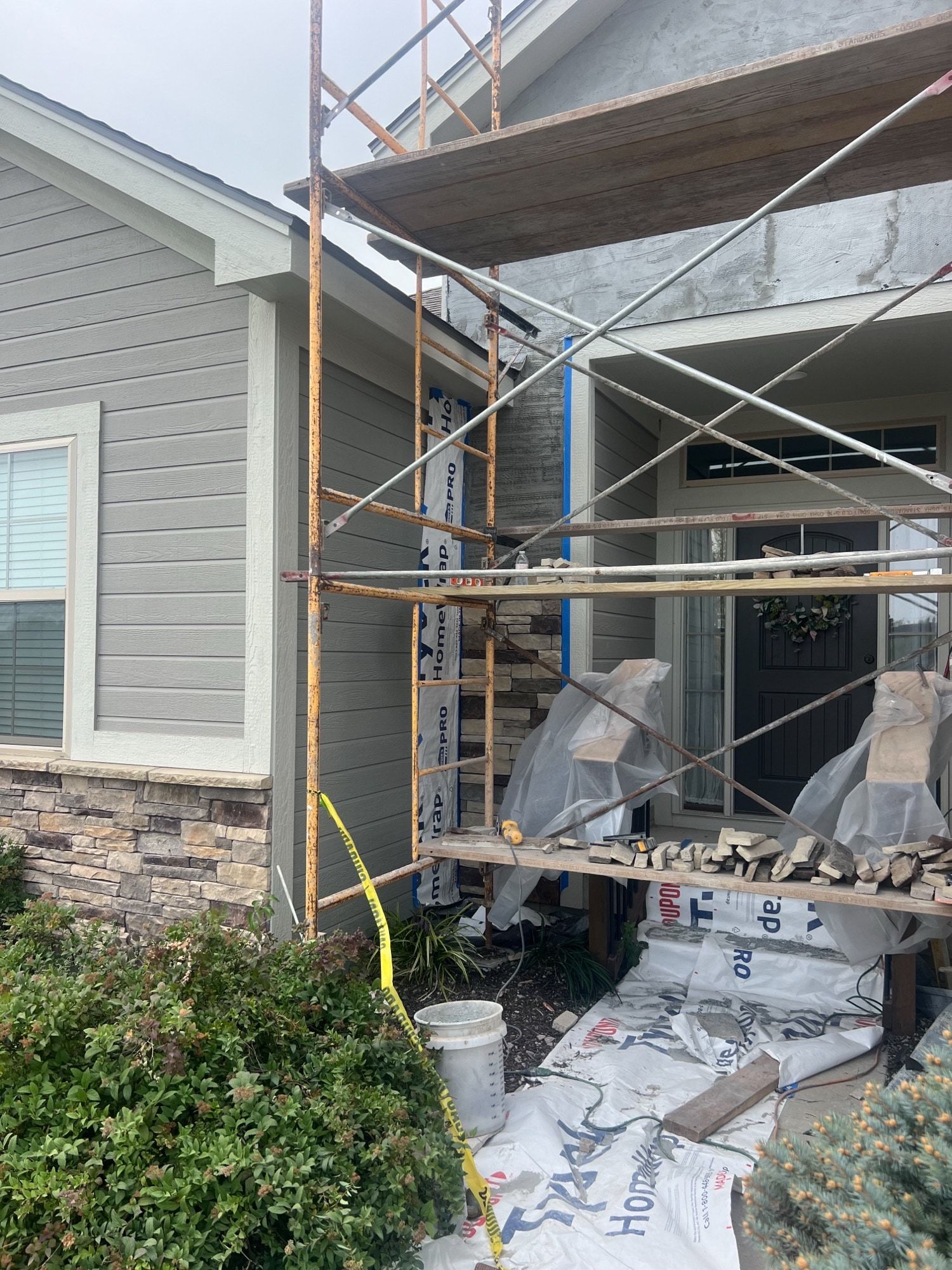 Scaffolding and stone mid-installation at the front entry during a Holden, Missouri whole home remodel