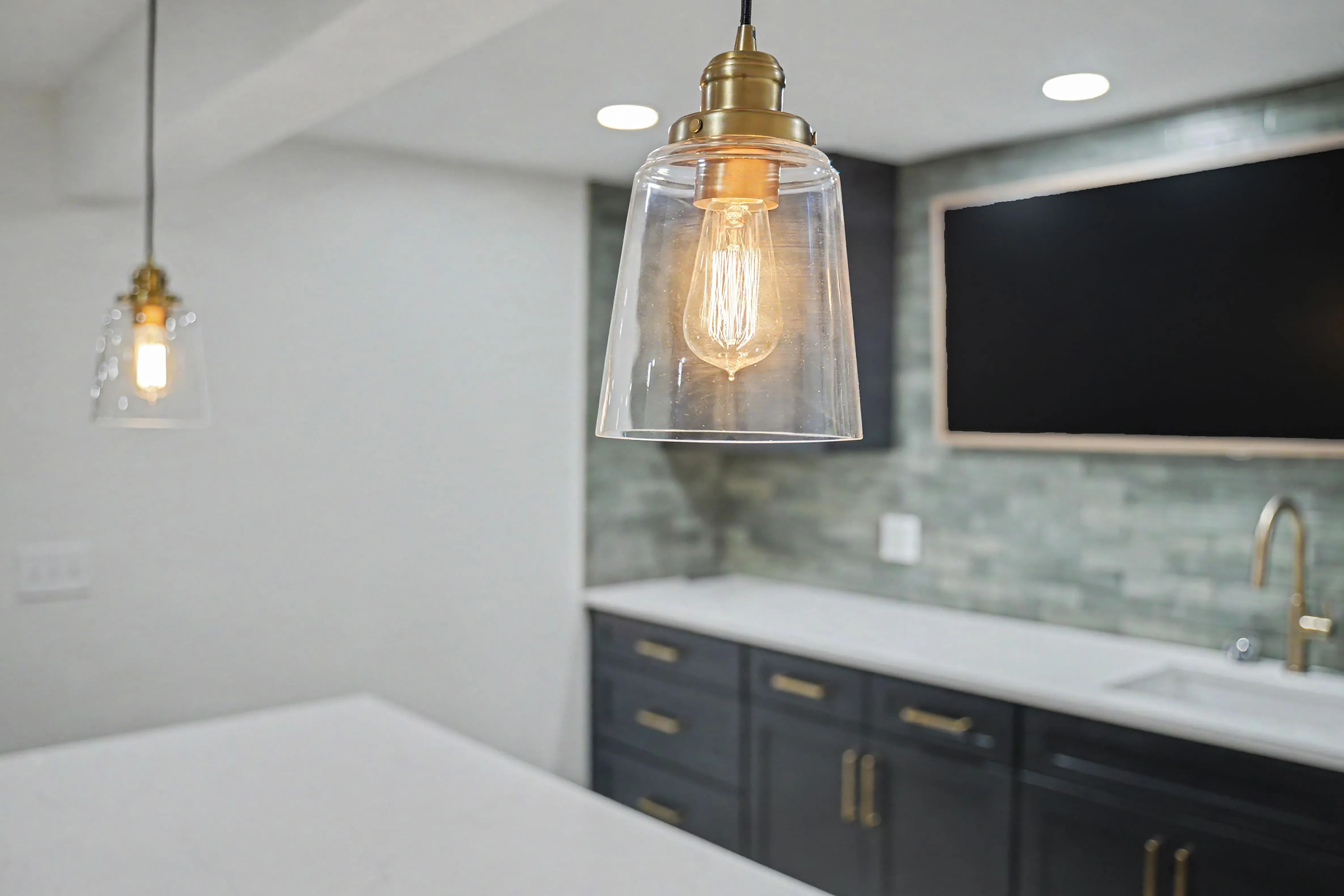 Brass pendant light detail above the kitchenette bar in a Prairie Village basement remodel