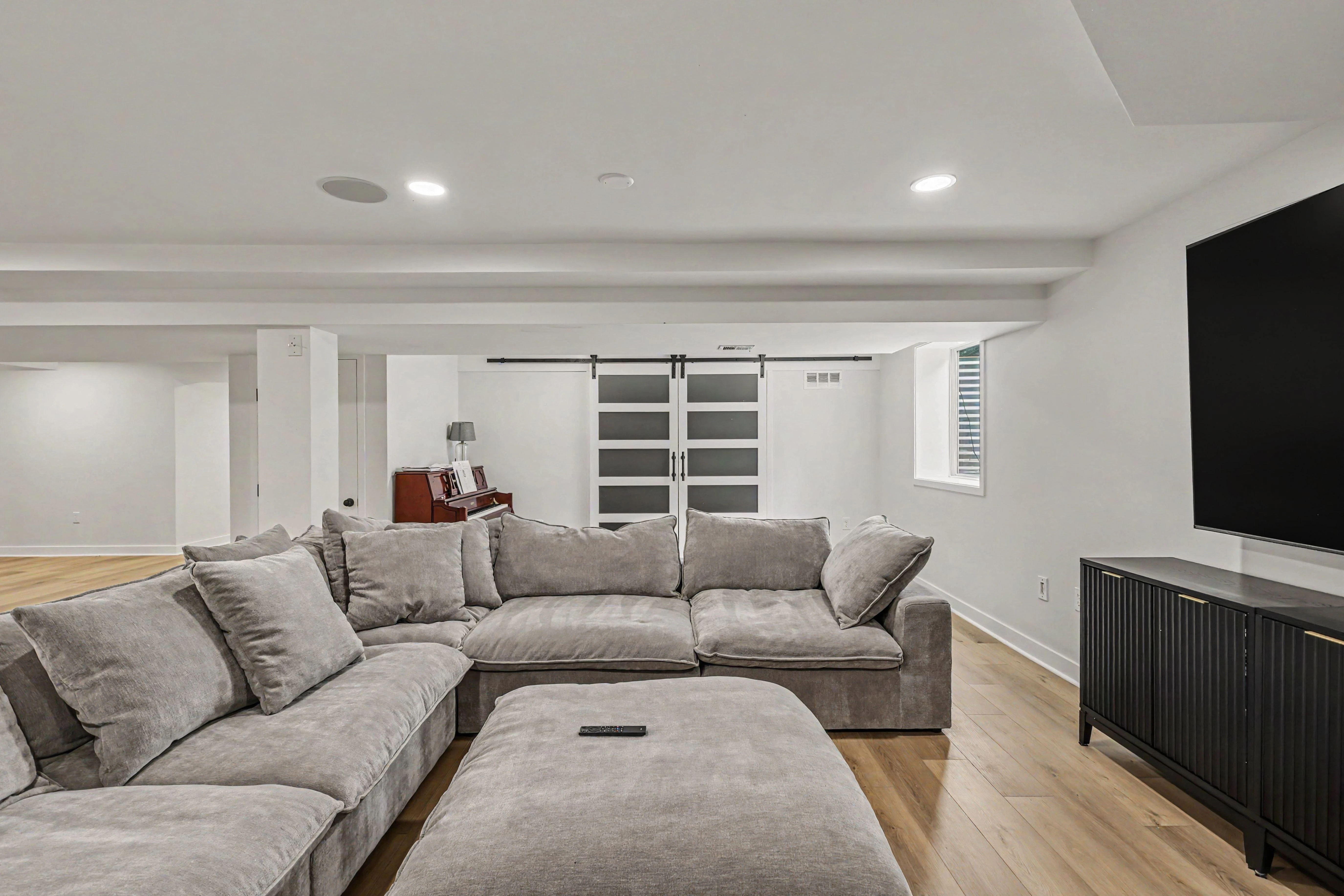 Finished basement family room with sectional, barn doors, and piano nook from a Prairie Village basement remodel