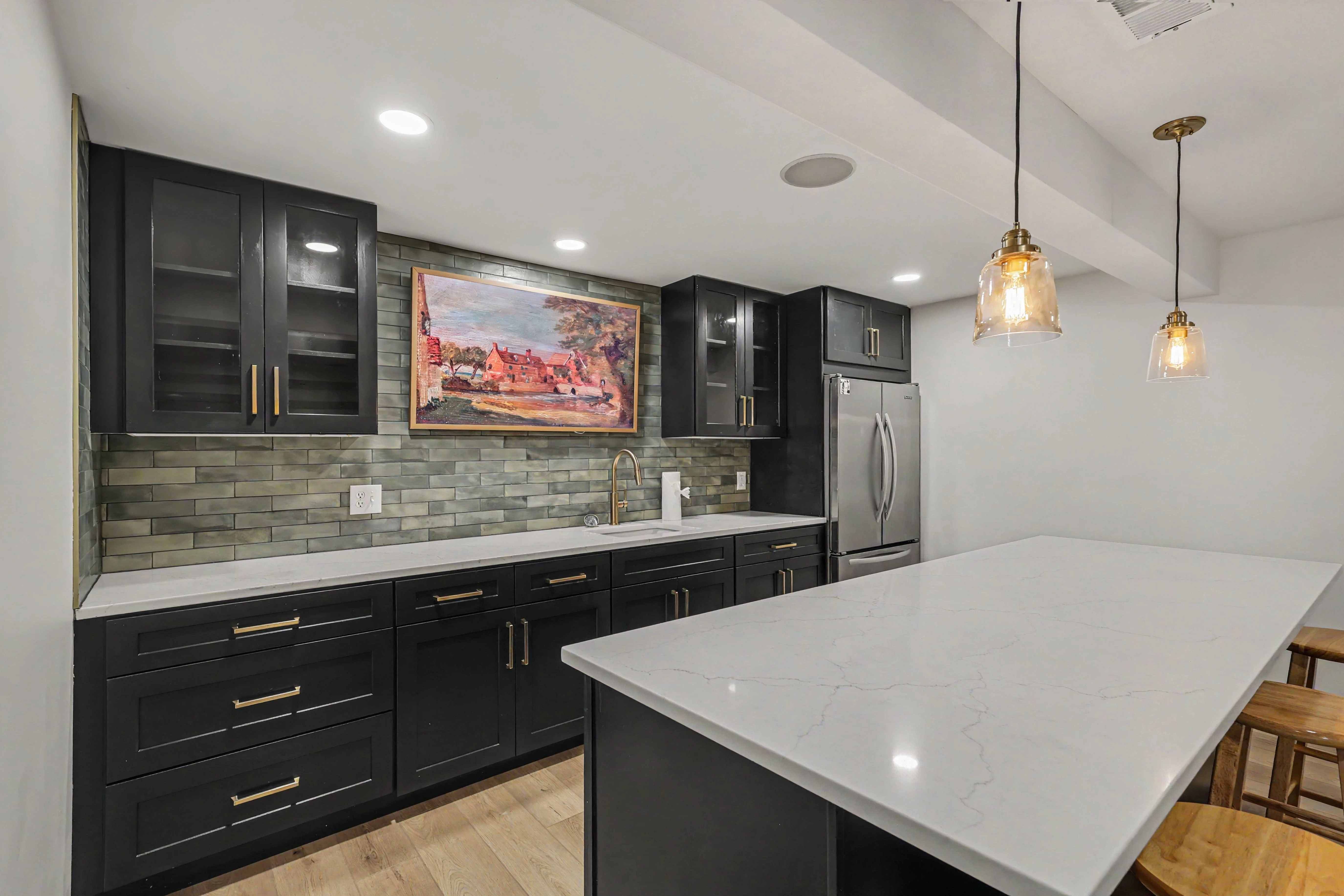 Black shaker cabinetry with brass hardware and quartz counters in a Prairie Village basement remodel kitchenette