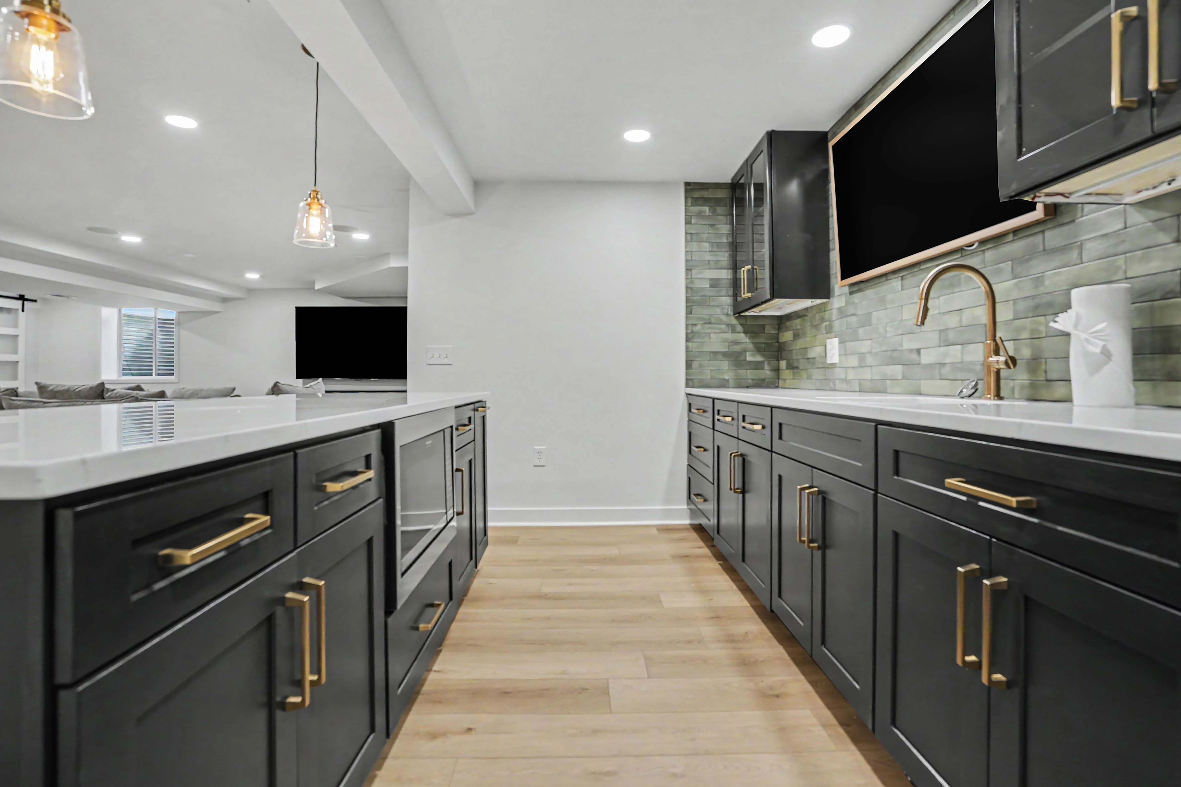 Finished basement kitchenette with black shaker cabinetry, quartz counters, and gold faucet
