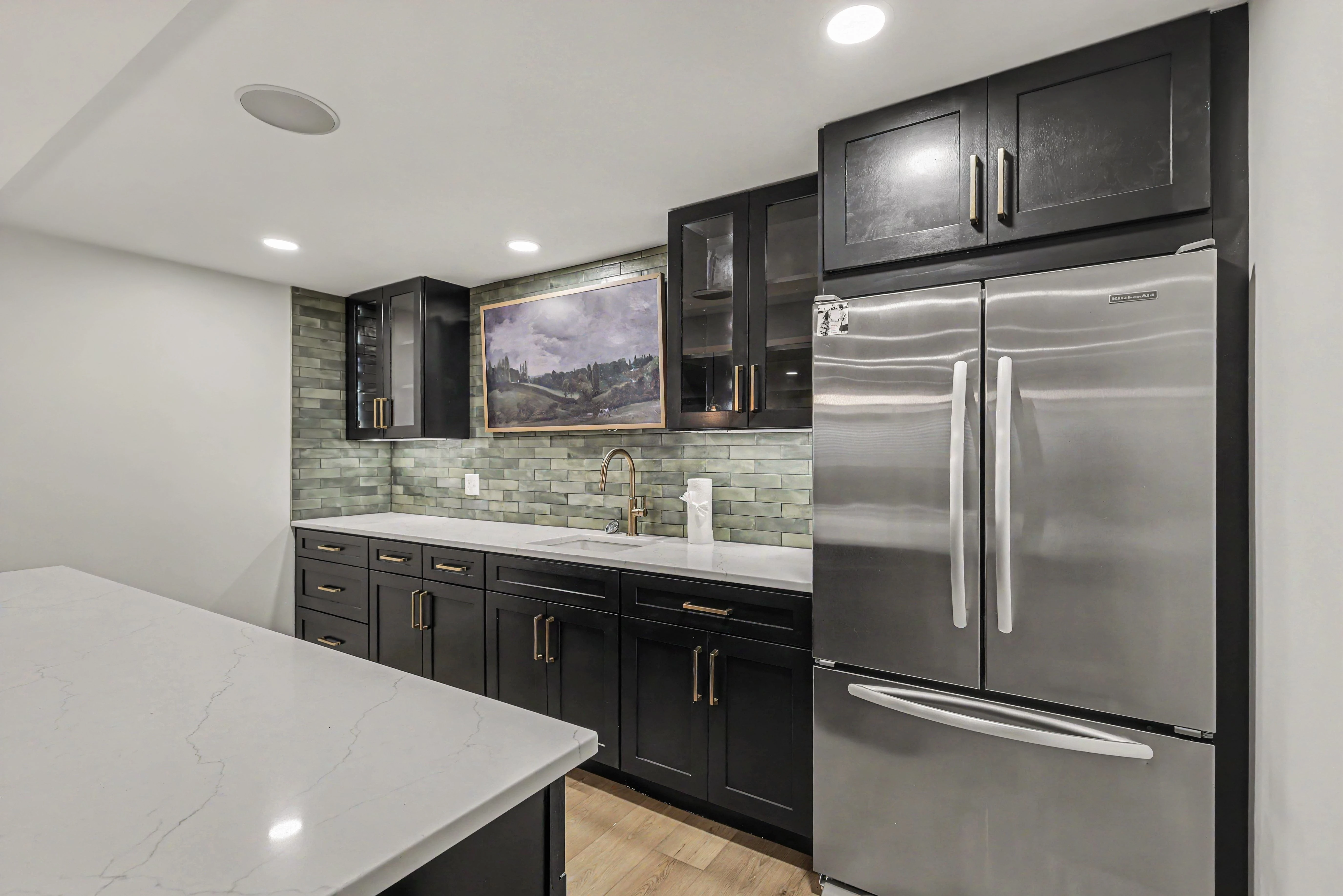 Basement kitchenette with glass upper cabinets and refrigerator in a Prairie Village basement remodel
