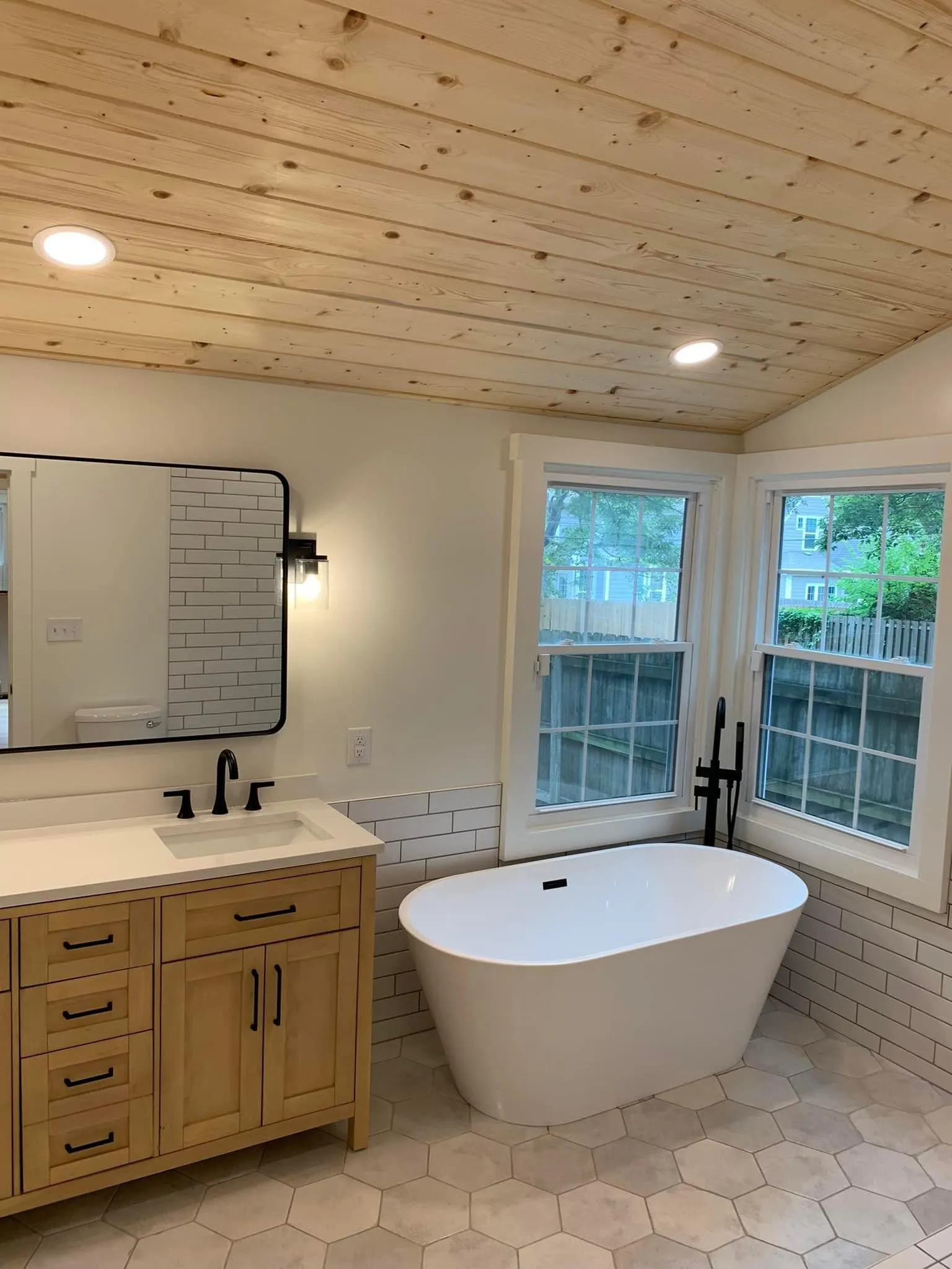 Freestanding tub beneath corner windows with a floor mounted filler in a Prairie Village bathroom remodel