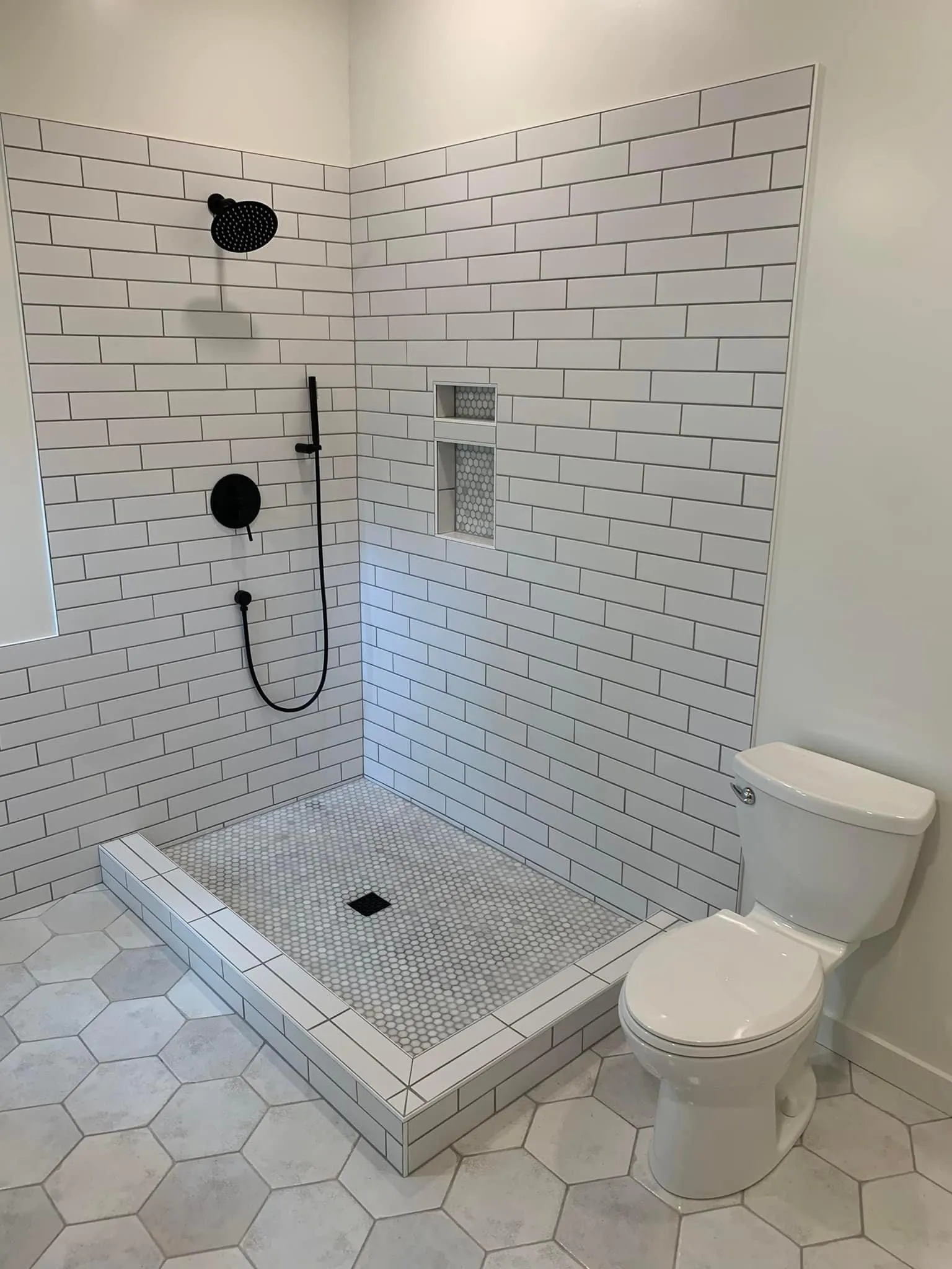 Tiled walk-in shower with matte black fixtures and a tiled niche in a Prairie Village bathroom remodel